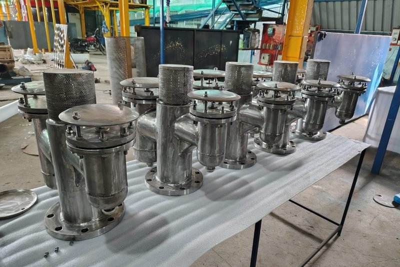 Production batch of stainless steel air release valves with perforated cowls laid out for inspection